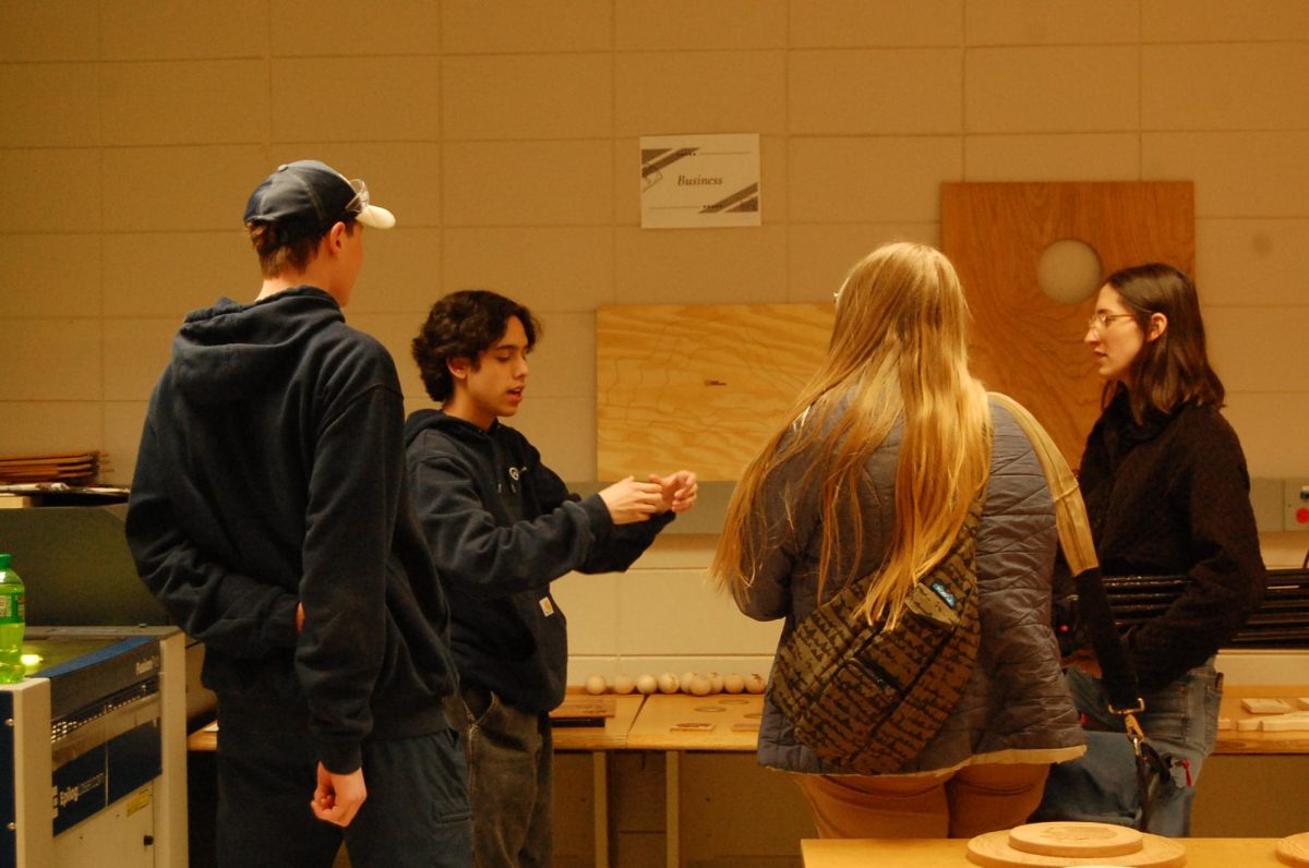 Senior Aeven Johnson-DeVera shows interviewers and junior Wilhelm Lewis how the Spartan Manufacturing vector creates wood work on May 6, 2026.