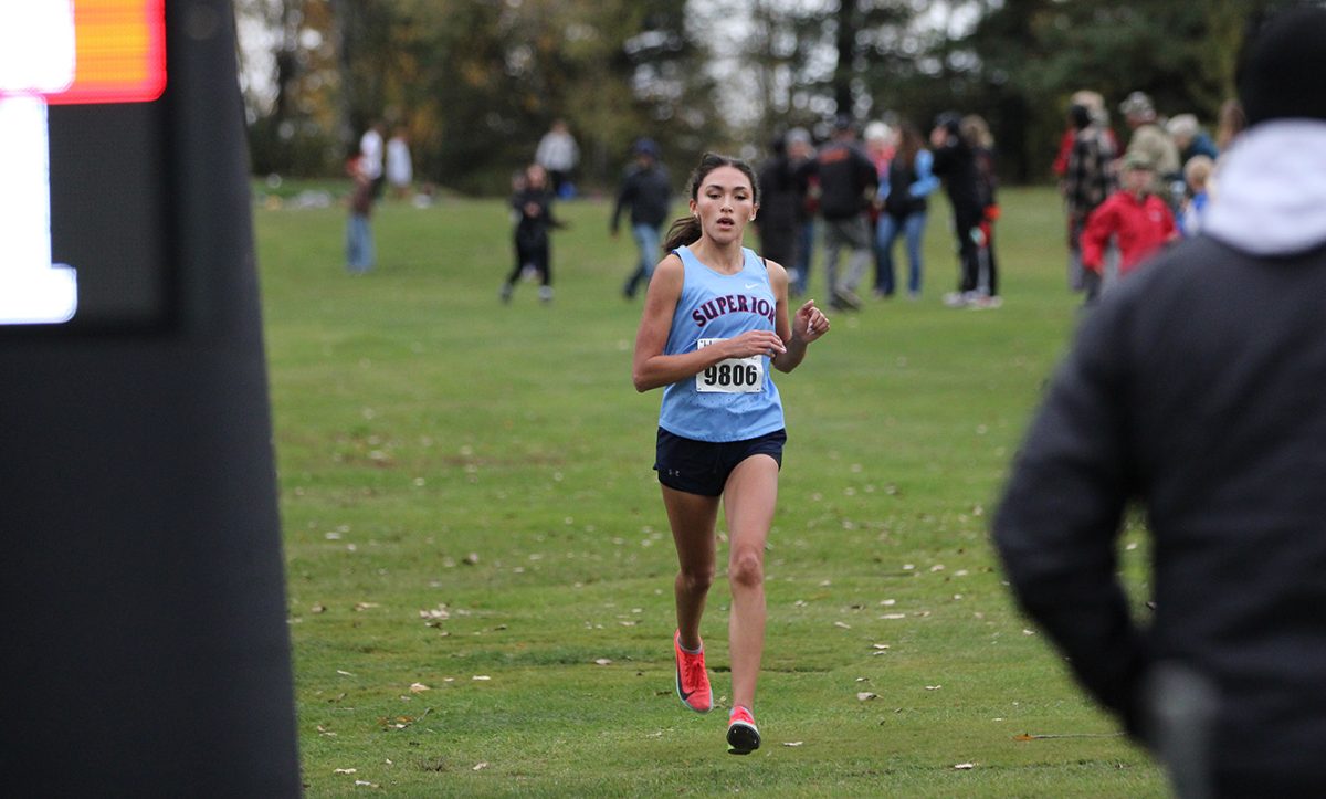 Senior Elena Almonte running towards the finish line at a cross country meet. 