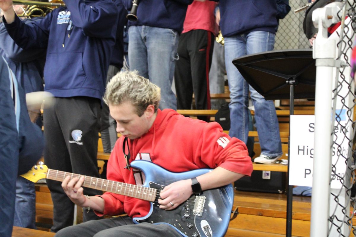 Senior Oso Fish tunes into the guitar as he plays a solo for pep band on Tuesday, Feb. 24 2026. Oso also played a solo of the National Anthem prior to the game starting.