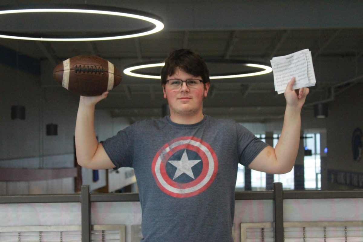 Conner Anderson proudly holds a football in one hand and his pep band music in the other.