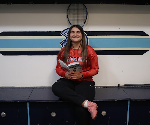  Junior Ava Dahl poses for a photo in front of her tennis racket while reading a book at SAHA on April 1, 2026. 