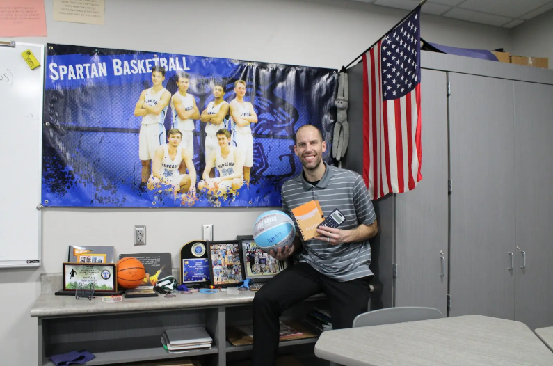 Jacob Smith posed in his classroom holding a basketball, an algebra notebook and calculator while in front of his medals and memorials of his past basketball teams on Mar 31.