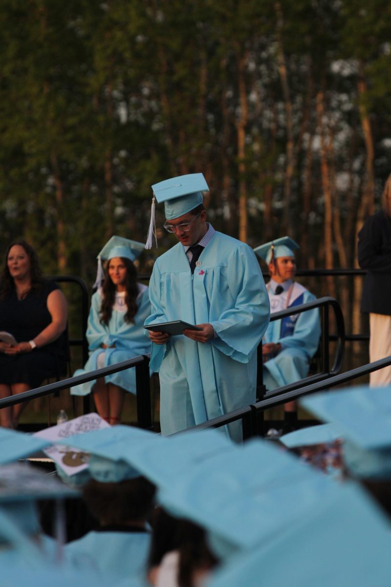 Senior Owen Wells looks down at his diploma while walking down the ramp after commencement on May 29, 2026.