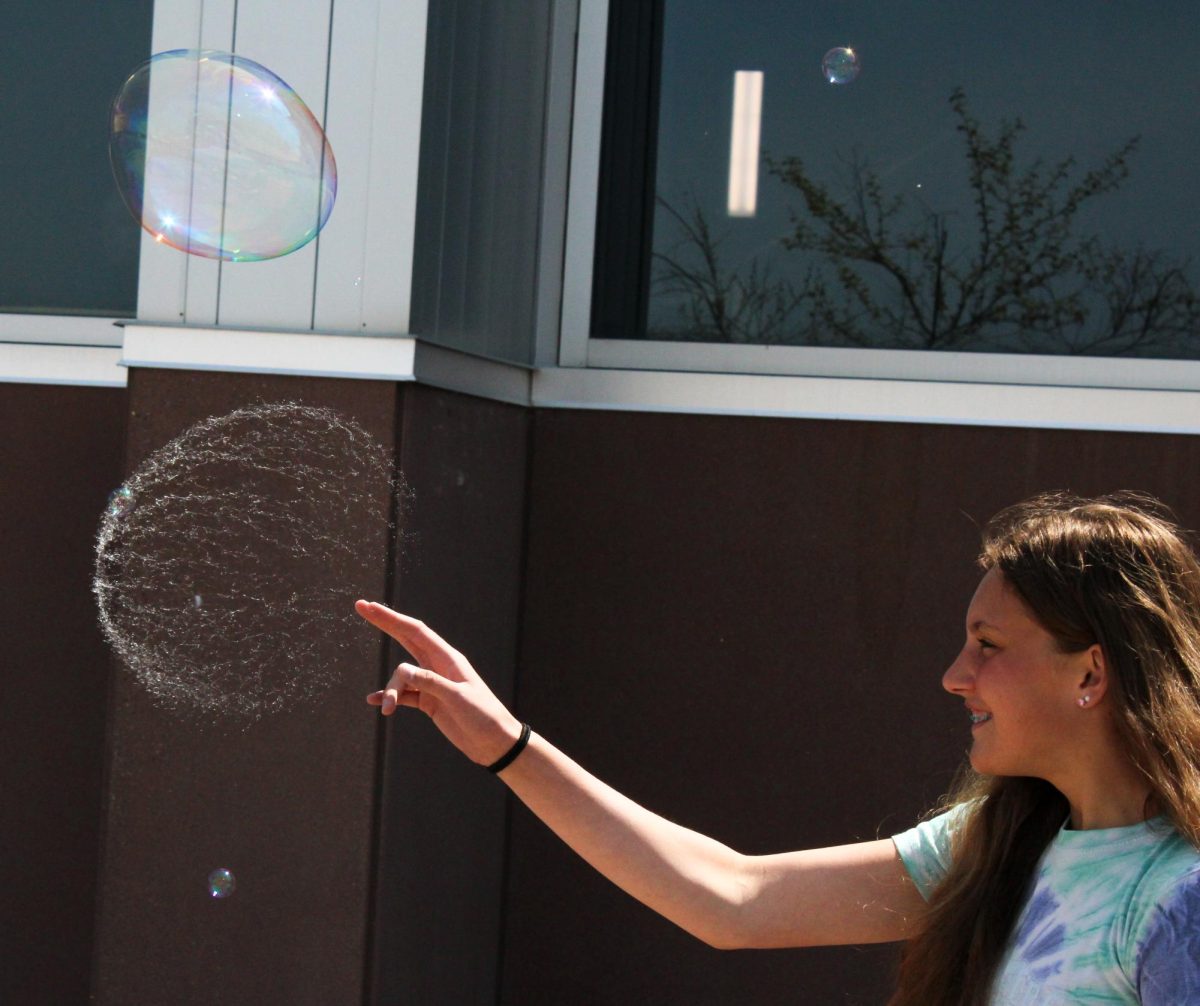 Sophomore Elizabeth Schmid reaches out and pops a bubble during a Spartan Spin photo challenge outside on June 3. 